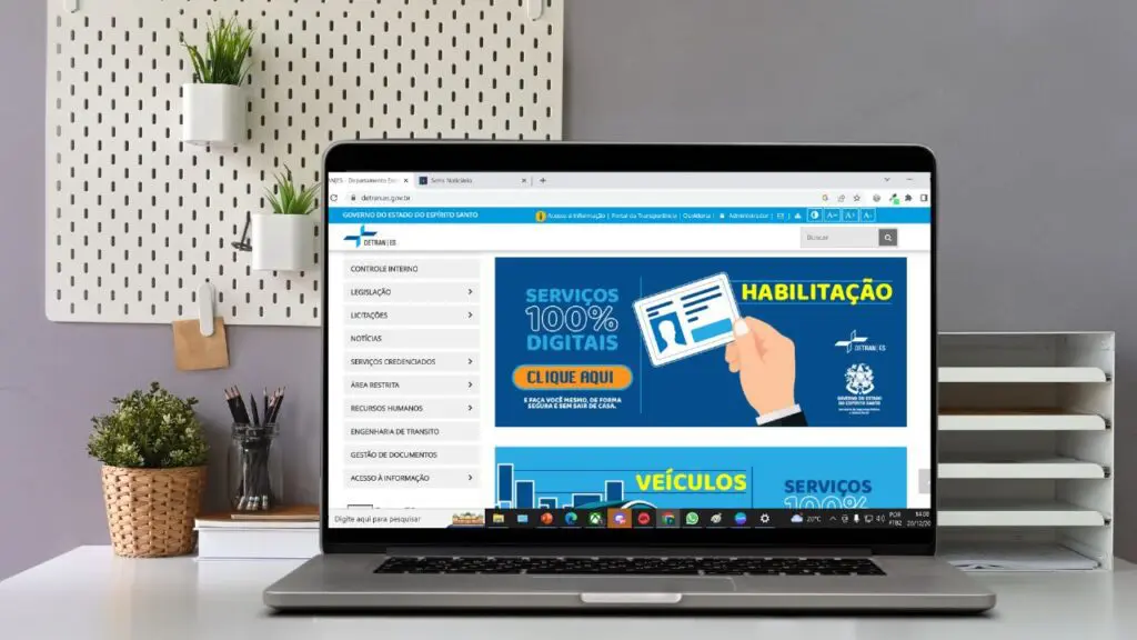 Detran ES passa oferecer dois novos serviços para os motoristas de forma totalmente digital Notebook sobre a mesa com aba do site do Detran ES
