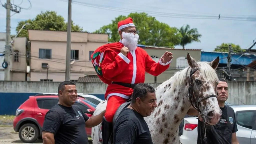 Polícia Montada leva alegria com o “Natal da Equoterapia” Instituições na Serra Policial fantasiado de Papai Noel, montado em cavalo branco com manchas marrons