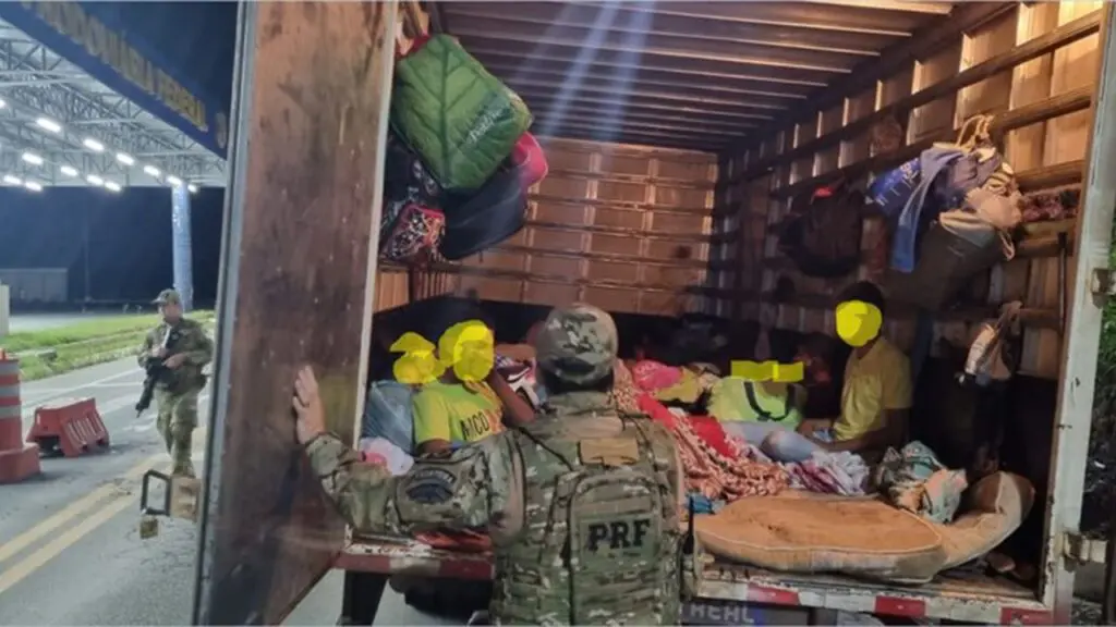 Coiote de turistas: PRF aborda caminhão baú recheado com 31 mineiros BR-262 no ES Policial abrindo porta de caminhão baú e encontrando pessoas sendo transportadas de forma irregular