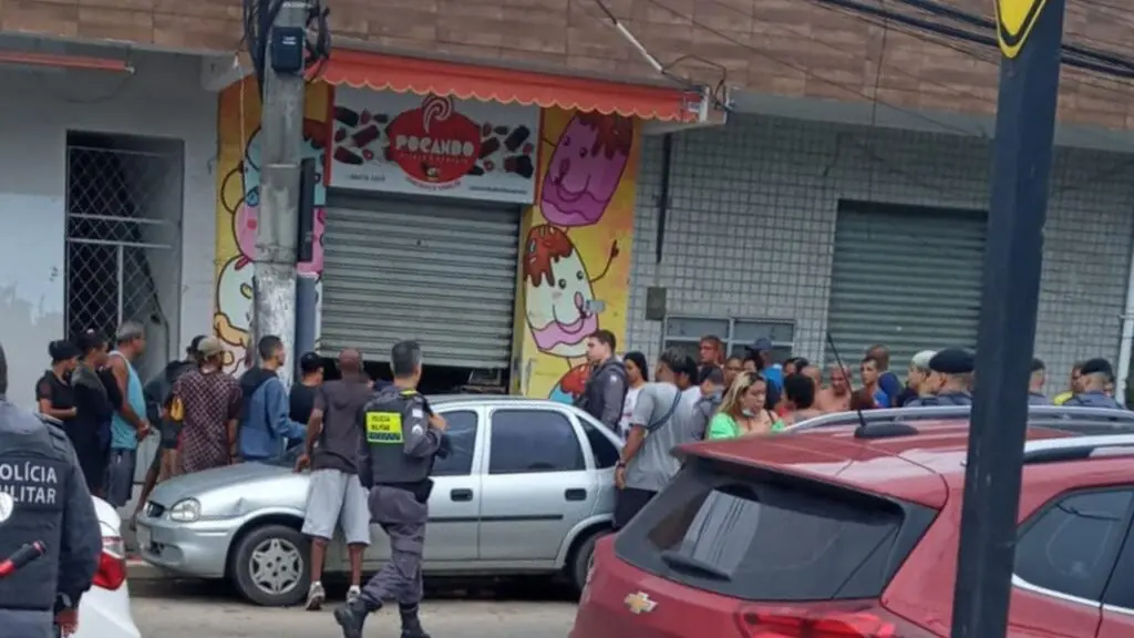 Multidão de pessoas paradas olhando homem baleado em frente a uma sorveteria