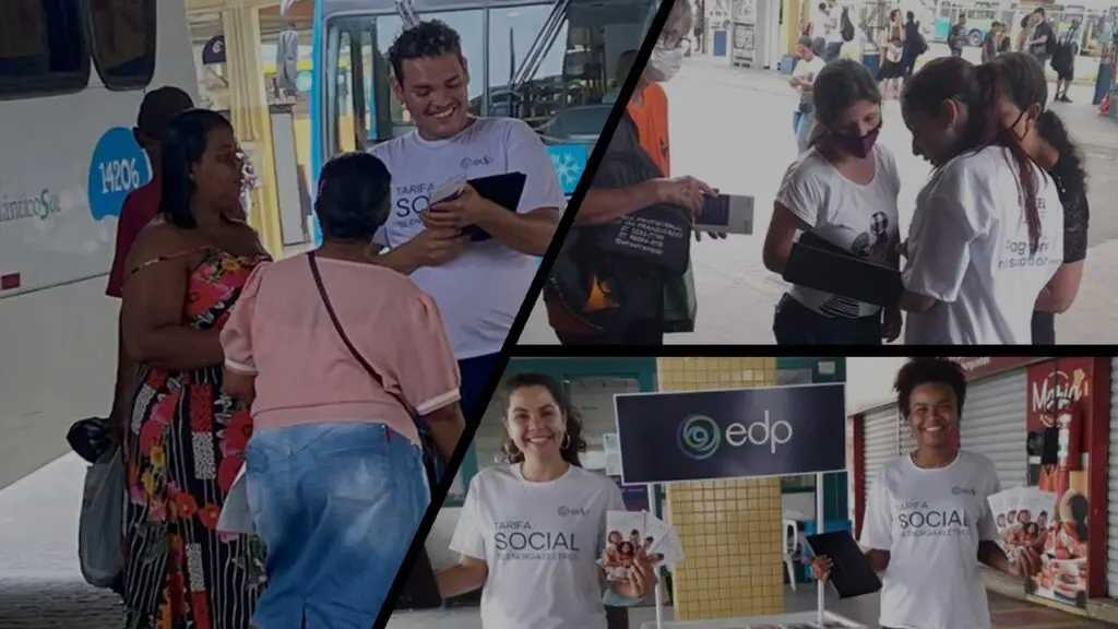EDP promove cadastro de Tarifa Social dentro dos terminais da Grande Vitória Funcionárias da EDP em terminal de ônibus, posando para foto com tablete e panfleto informativo sobre benefício Tarifa Social