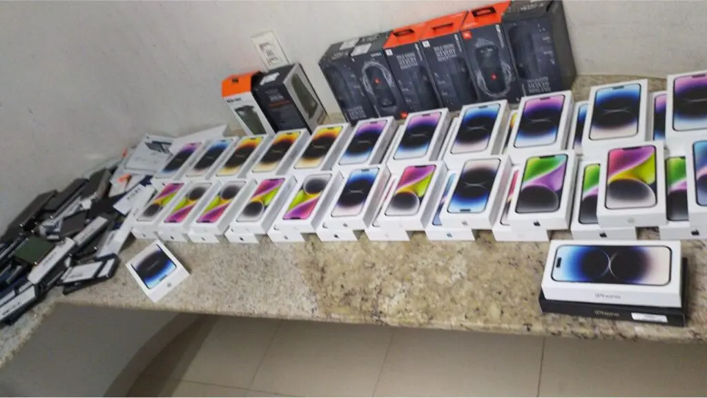 PRF prende quadrilha e recupera carga roubada de iPhones avaliada em 1 milhão reais em na Serra Sobre a mesa da Polícia Rodoviária Federal centenas de iPhones e outros produtos eletronicos recuperados pelas equipes Polícia Rodoviária Federal