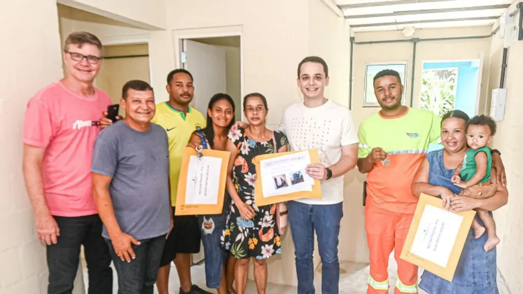 Casa Feliz e Segura: projeto da Prefeitura de Vitória beneficia mais três famílias com novas casas Foto de 3 famílias com documentos e chaves das novas casas reconstruídas pelo projeto reconstrução, e no centro da foto o Prefeito de Vitória,