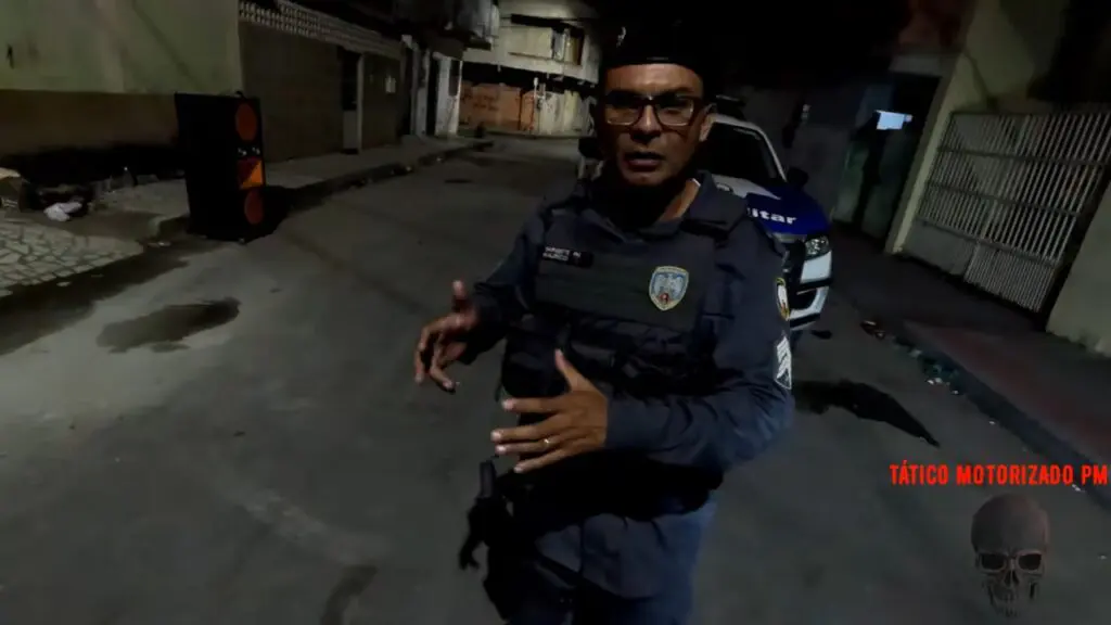 Vídeo: Polícia Militar detona baile clandestino após denúncias anônimas na Serra Foto do Sargento da 14ª Cia ind. Mauricio Sousa em frente a uma viatura da Polícia militar explicando o ocorrido na ocorrência