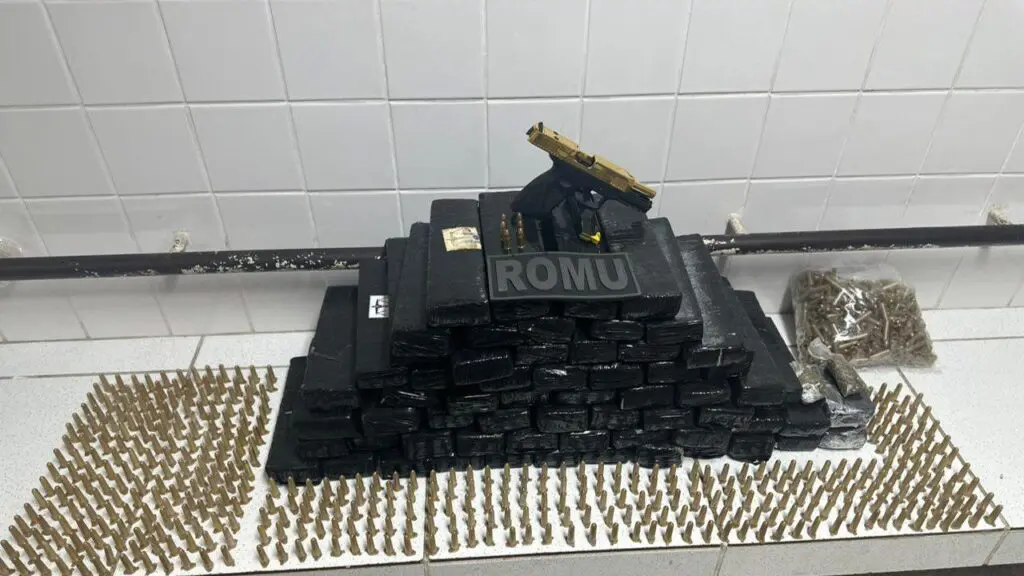 Guarda da Serra detém dois queimados por tráfico após encontrar arma e 40 kg de maconha Sobre uma bancada branca da 3ª Delegacia localizada na cidade de Serra, 62 tabletes de maconha, em embalagem da cor preta (40kg), 428 pinos de cocaína, duas buchas de maconha, uma pistola Taurus G3C calibre 9mm, com detalhes em dourado, seis munições calibre .9mm e R$ 2.300 em espécie.