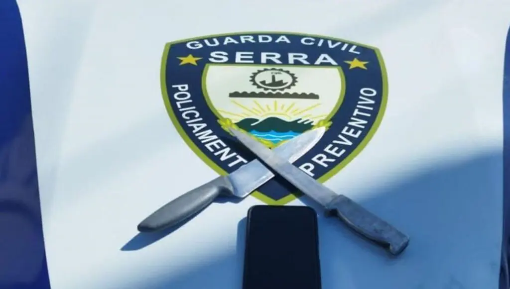 Guarda da Serra prende ‘cracudo’ após assaltar uma mulher em ônibus do sistema Transcol Foto de duas facas cruzadas e um celular sobre o capo de uma viatura da Guarda Municipal da Serra