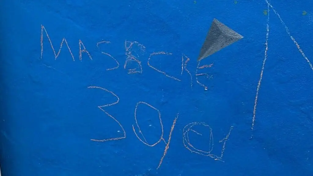 Adolescentes são flagrados por câmera de segurança pichando ameaça em muro de escola na Serra Foto de um muro azul riscado dom a tentativa de escrever "Massacre 30/01" mas está escrito "Masscre 30/01"