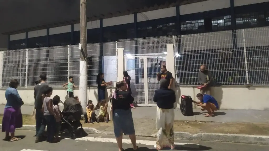 Grupo religioso realiza culto pedindo proteção em frente de escola municipal na Serra Um grupo de aproximadamente 20 pessoas em frente a uma escola na Serra, realizando um culto.