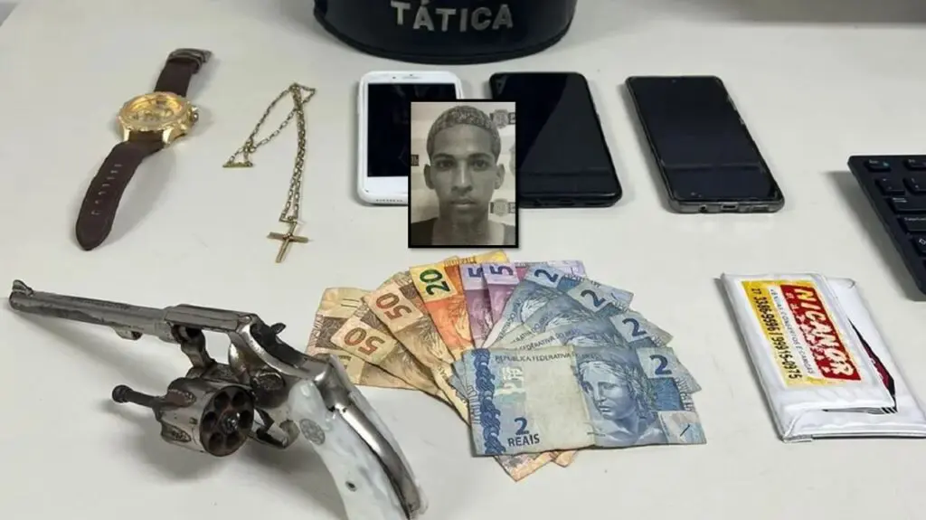PM prende assaltante na Serra acusado de roubar marmoraria na cidade de Fundão Arte com duas imagens, na primeira sobre a uma mesa branca um revólver calibre 32, um relógio, um cordão, uma quantia de R$ 188 e três aparelho celulares.