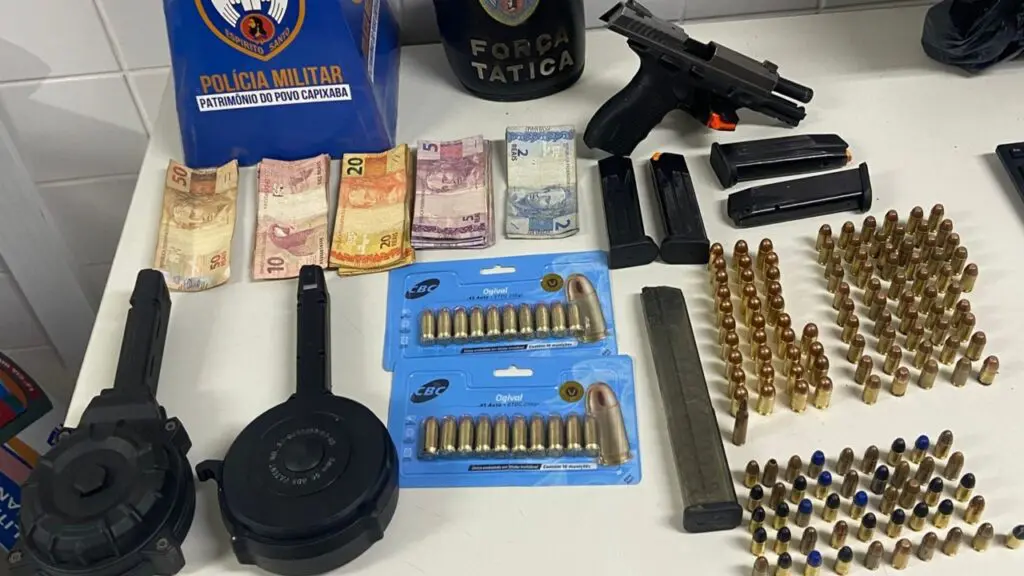 Sobre uma mesa branca 01 pistola calibre .40 com numeração raspada 05 carregadores calibre .40 01 carregador de pistola calibre 9mm com capacidade para 30 munições 02 carregadores "caracol" de pistola calibre 9mm com capacidade para 50 munições 54 munições calibre .45 55 munições calibre .40 46 munições calibre 9mm 01 munição calibre 556 R$ 510,00 em espécie