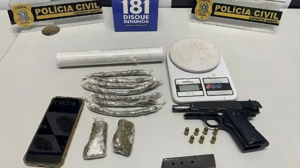 Polícia Civil prende suspeito de gerenciar ponto de venda de drogas na Serra Foto sobre uma mesa uma pistola .380, 7 munições, um carregador, porções de maconha embaladas para venda, material para embalar drogas e uma balança de precisão.