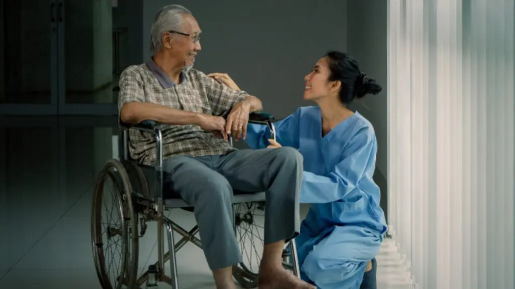 Homem com deficiência e ao lado sua cuidadora