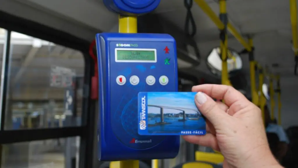 Entenda quem tem direito de receber o vale-transporte Foto de uma pessoa segurando o vale transporte para ultrapassar a catraca.