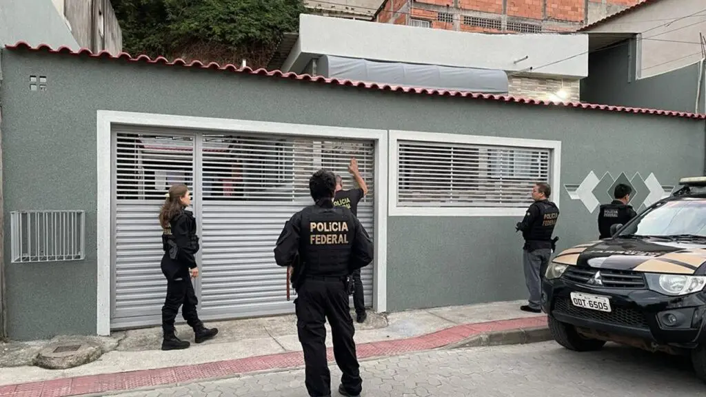 Polícia Federal prende mulher na Serra acusada de falsificação de documentos para visto americano 4 agentes da Policia Federal em frente a uma casa, prontos para cumprir um mandado de prisão