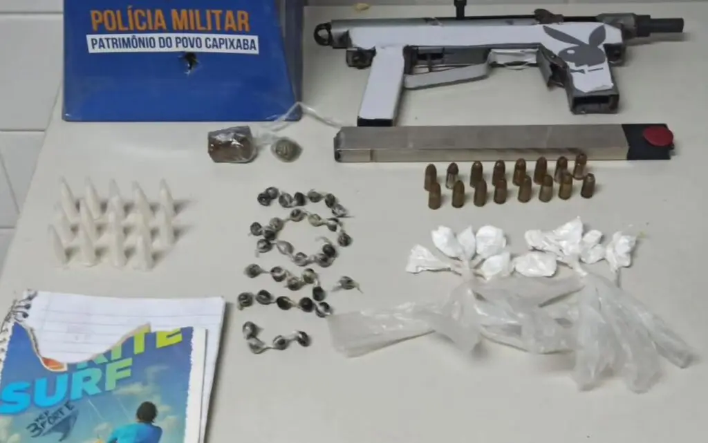 Polícia Militar prende traficante armado com submetralhadora vacilando na pista na Serra Sobre uma mesa branca uma submetralhadora "craftada pelos crias" calibre 380 com 16 munições e um carregador. Além da arma, também foram apreendidas 34 unidades de haxixe, 14 pinos de cocaína, 10 papelotes de cocaína e 2 buchas de maconha.