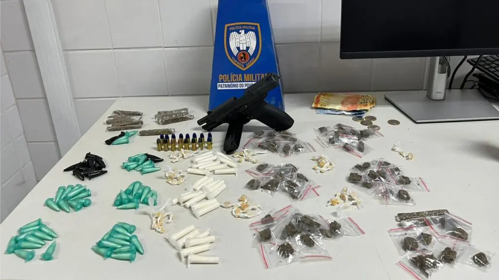 Polícia Militar flagra adolescente recheado de drogas na biqueira em Planalto Serrano Foto de apreensão da PM, sobre uma mesa branca uma pistola 9mm, com numeração raspada, um carregador e 16 munições do mesmo calibre, além de 95 pinos de cocaína, 73 pedras de crack, 71 buchas de maconha e a quantia de R$ 181,00 em dinheiro