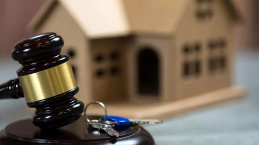 Foto de um martelo de leilão, uma casa e chave, simulando vendido