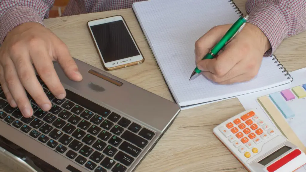 Como saber se o seu nome está envolvido em uma dívida? Foto de uma pessoa calculando as dívidas