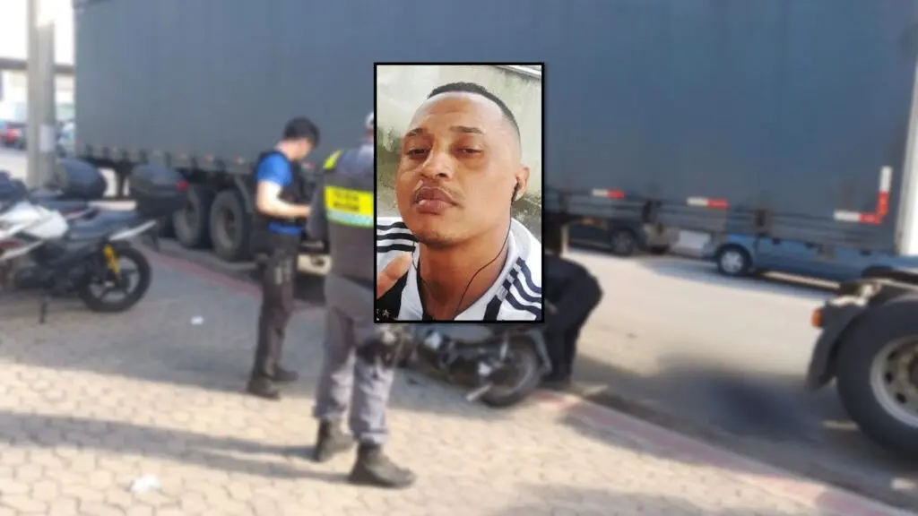 Tragédia no Trânsito: Motociclista morre após ter moto arrastada por carreta na Serra Foto de uma motocicleta destruída embaixo de uma carreta, com um policial militar e um civil analisando o local