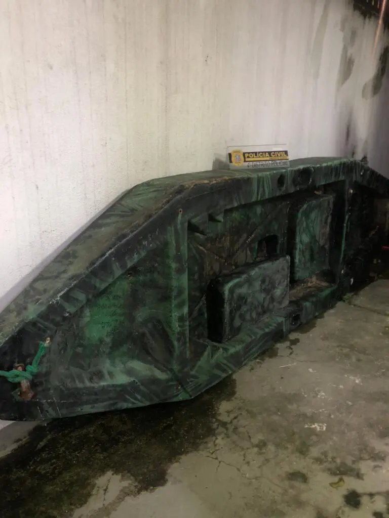 Barco recuperado pela Polícia Civil encostado em uma parede.