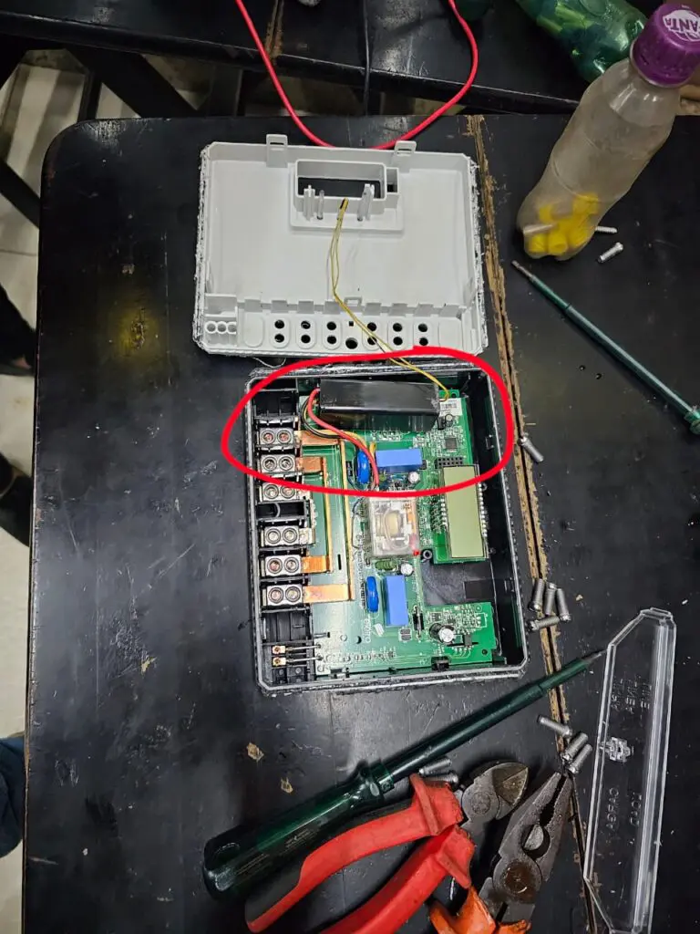 Foto da adulteração no medidor de energia, durante a inspeção os técnicos descobriram o furto em dois medidores: em cima de uma mesa um medidor aberto, com outras ferramantas sobre a mesa