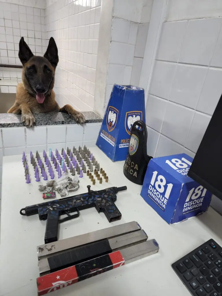 Apreensões da Polícia Militar sobre uma mesa 21 buchas de maconha, 111 pinos de cocaína, uma submetralhadora "craftada pelos crias" (fabricação semi industrial) calibre .380, com dois carregadores sobressalentes e 12 munições calibre .380.