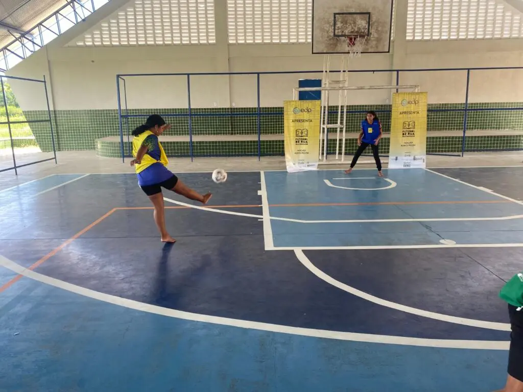 Projeto Futebol de Rua duas meninas jogando bola em uma quadra de society.