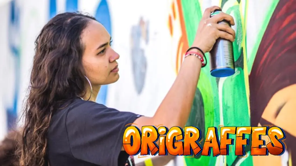 Uma mulher com uma lata de spray grafitando um muro.