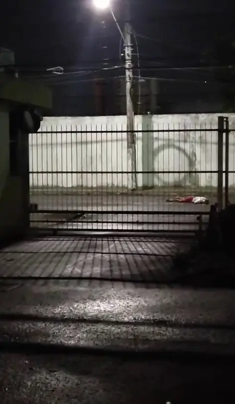 Vítima do homicídio caída no meio do asfalto.