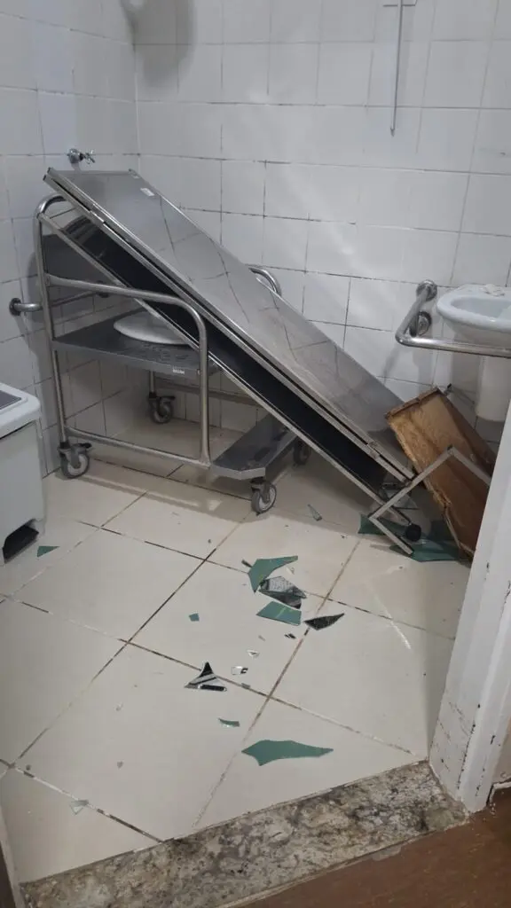 sala onde o fugitivo estava sob custodia com macas e vidros destruidos.