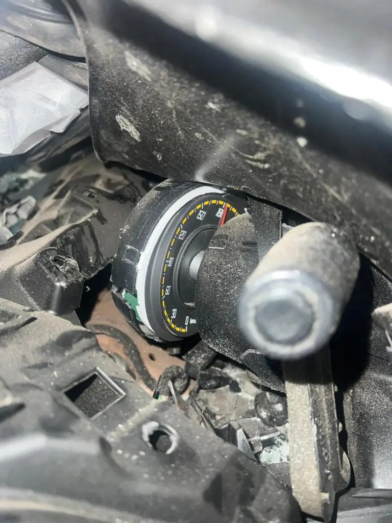 Velocímetro do veículo marcando a velocidade de 180 km/h, em meio a ferragens.