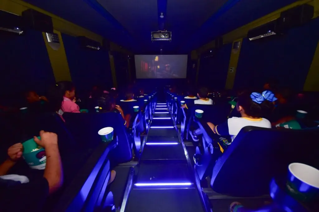 Uma sessão de cinema dentro da carreta com dezenas de pessoas assistindo um filme.