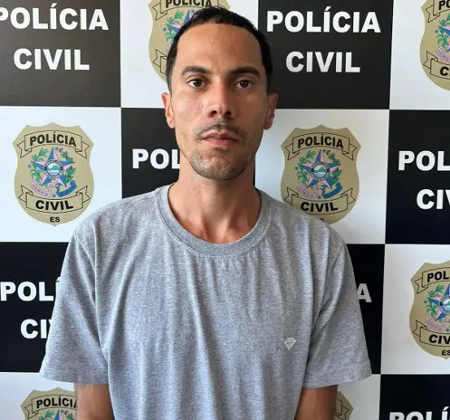 Foto de um homem (Arthur Ribeiro Brandão, de 26 anos), preso pelo assassinato de um jovem, no fundo o banner da Polícia Civil.
