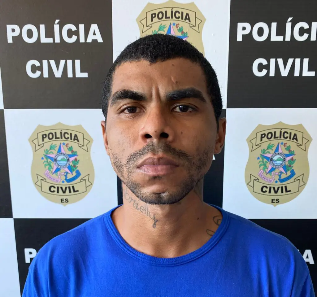 Foto de um homem (Roger Passos Gonçalves, de 27 anos), preso pelo assassinato de um jovem, no fundo o banner da Polícia Civil.
