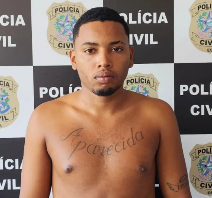 Foto de um homem (Gabriel Ferreira Adão, de 22 anos), preso pelo assassinato de um jovem, no fundo o banner da Polícia Civil.
