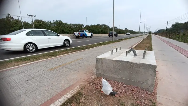 Imagem de uma base de concreto, no canteiro central de uma rodovia, com veículos trafegando na pista.