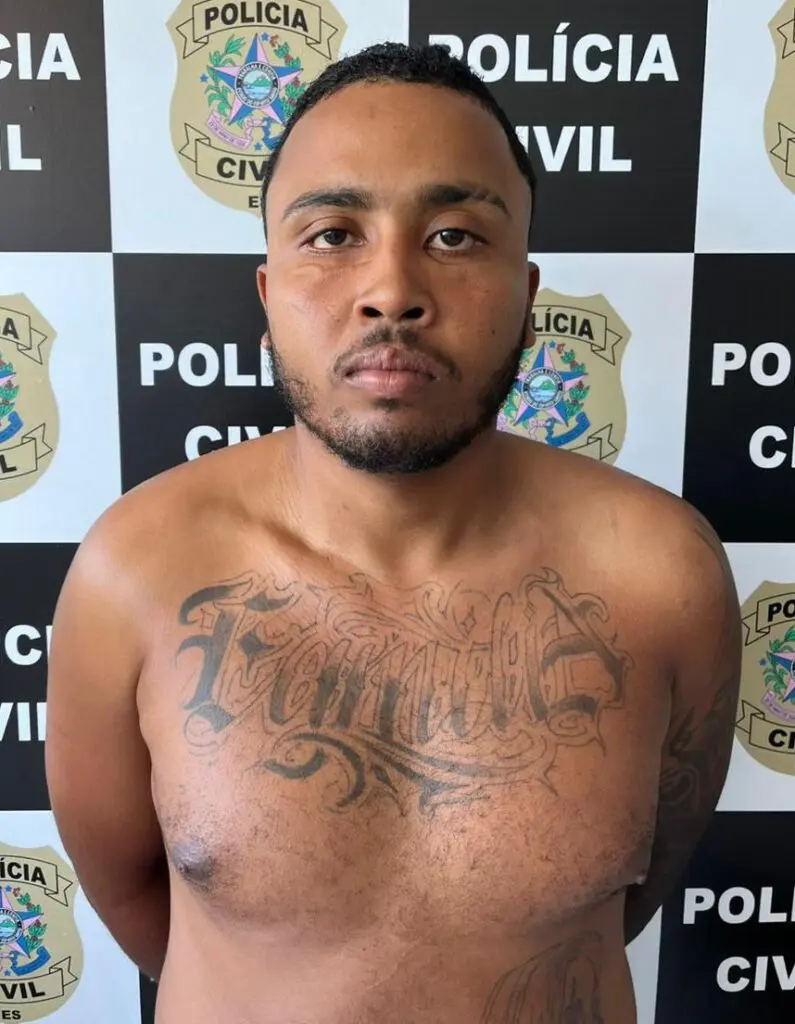 Um homem com os braços para trás em uma delegacia (Sujeito era um dos dez criminosos mais procurados de MG).