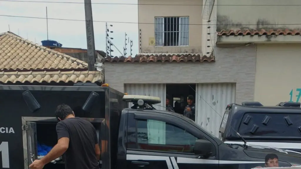 Fachada da casa onde aconteceu o crime, com a viatura do IML