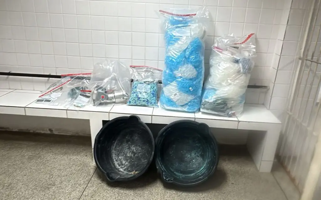 Sobre uma bancada matérias usados pelo tráfico apreendidos pela Polícia Militar embalados em sacos.