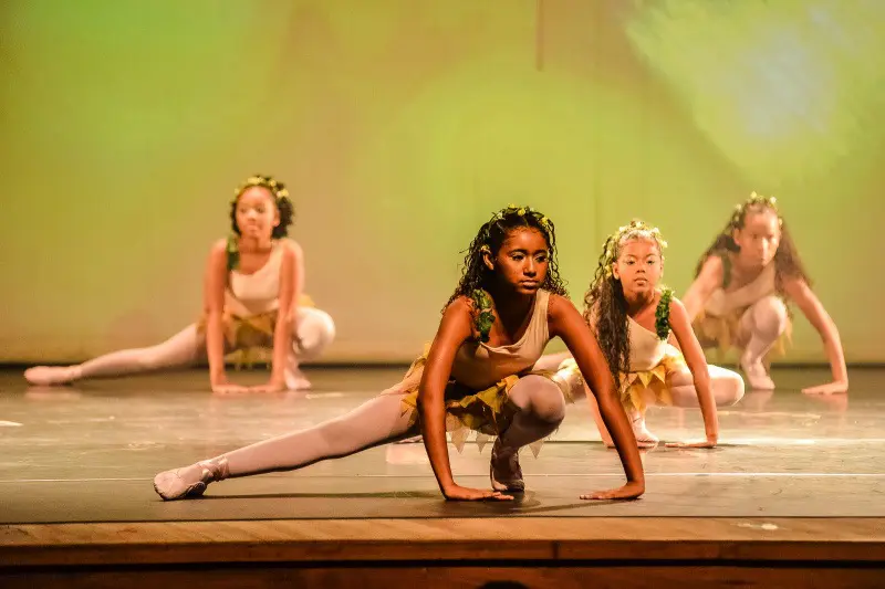 Quatro alunas de ballet da Fafi durante uma aula, realizando uma coreografia.