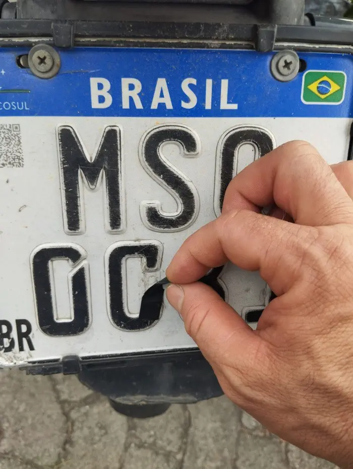 Um agente da Guarda de Vitória, puxando um pedaço de fita isolante, que era usada para adulterar a documentação da moto.
