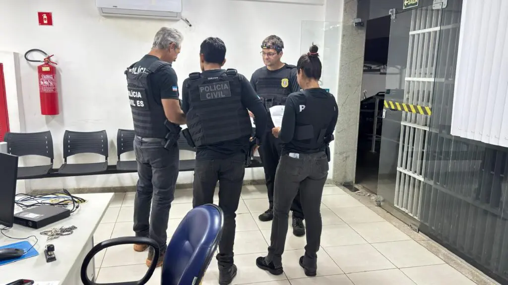 Quatro policiais civis reunidos no saguão de uma delegacia.