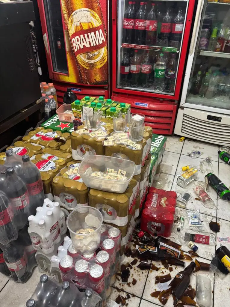 Imagem interna de um bar com diversas garrafas quebradas espalhadas pelo chão.