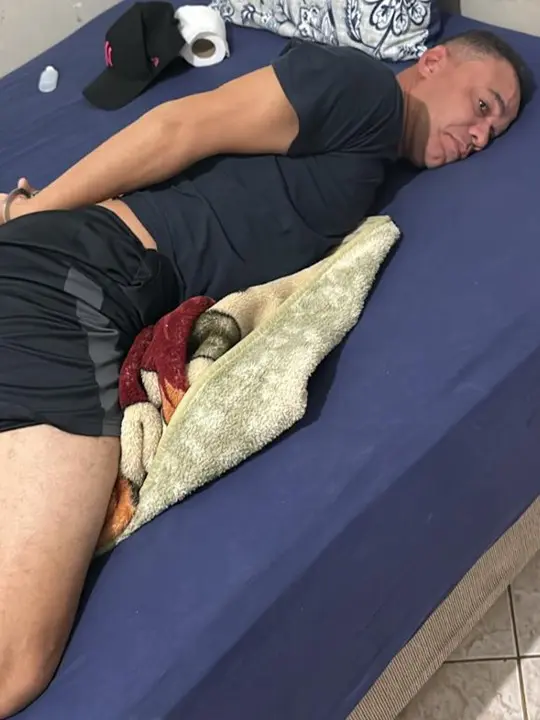 Foto de um homem (Leonardo Costa de Souza, 39 anos), preso com as mãos para trás, deitado em uma cama algemado, por fazer parte de uma quadrilha que furtou diversas instituições financeiras em vários estados do Brasil.