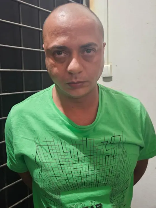 Foto de um homem (Rondinelli Batista Antônio, 39 anos), com as mãos para trás preso por fazer parte de uma quadrilha que furtou diversas instituições financeiras em vários estados do Brasil.