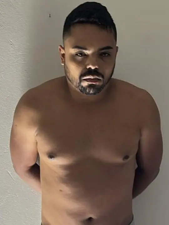 Foto de um homem (Ricardo Moreira Gomes, 34 anos), com as mãos para trás preso por fazer parte de uma quadrilha que furtou diversas instituições financeiras em vários estados do Brasil.