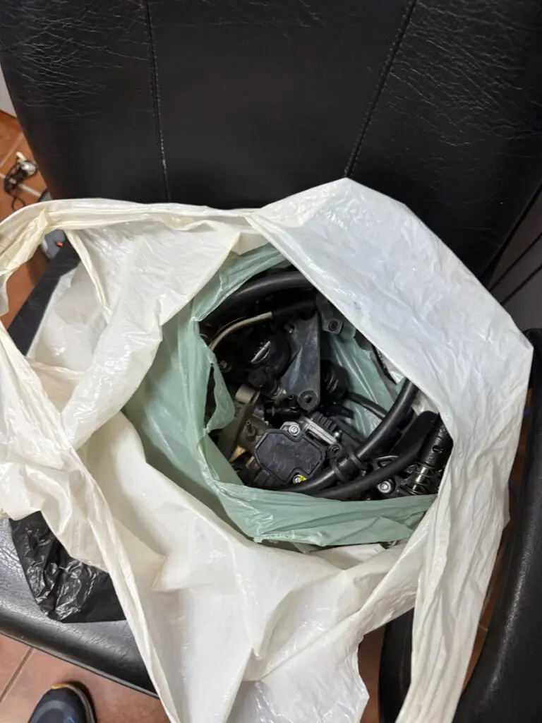 Sobre uma cadeira, uma sacola com peças de motos dentro.