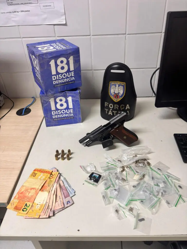 Imagem de uma mesa de uma delegacia, com diversos itens apreendidos expostos: Uma pistola calibre 380, R$103,00 em espécie e 78 envelopes de plástico pequenos contendo Haxixe.