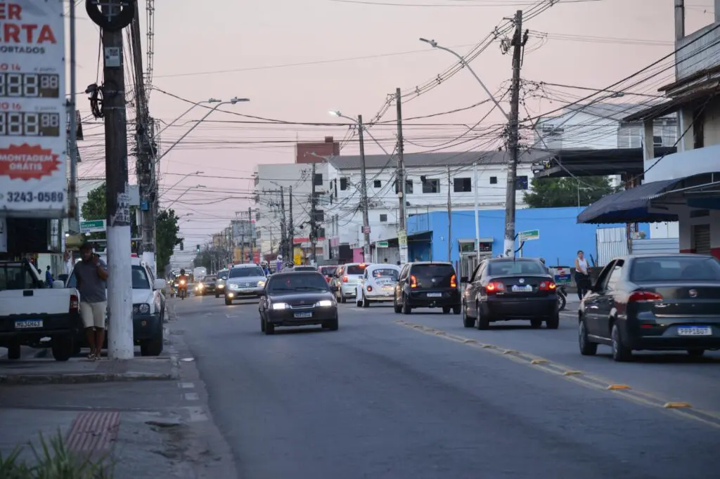 Imagem de uma avenida com carros trafegando em duas pistas em direções diferentes.