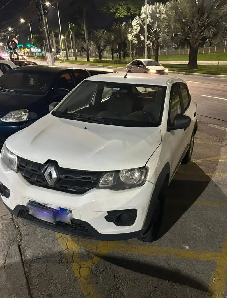 Um carro modelo Renault Kwid branco estacionado em um pátio.